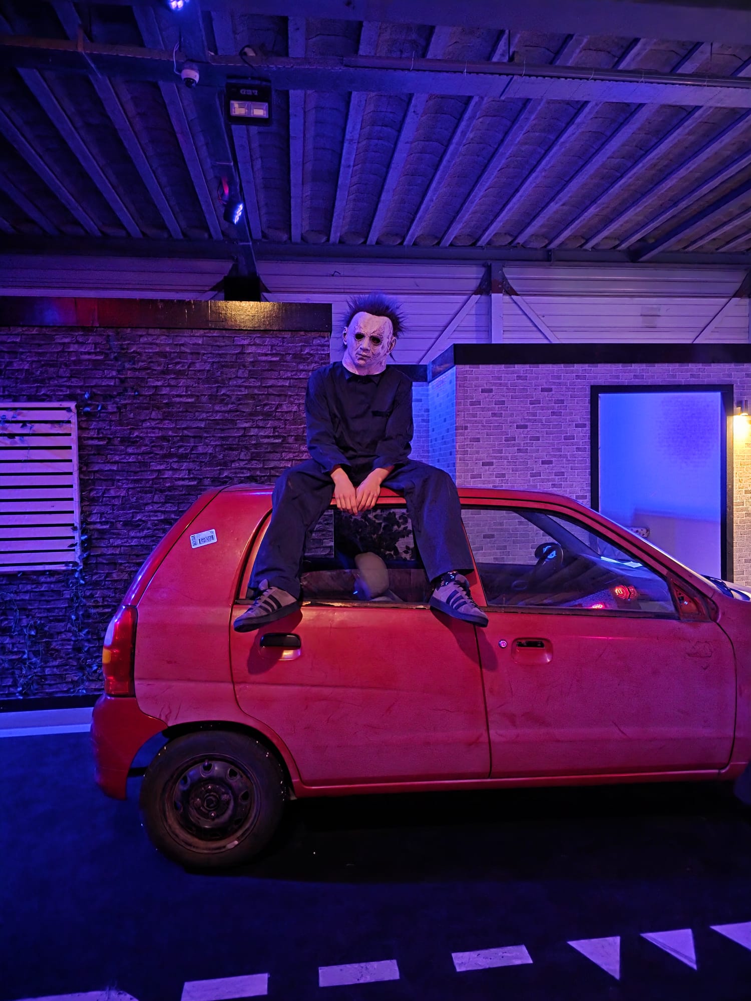 A masked Halloween actor on a red car at Unit 13